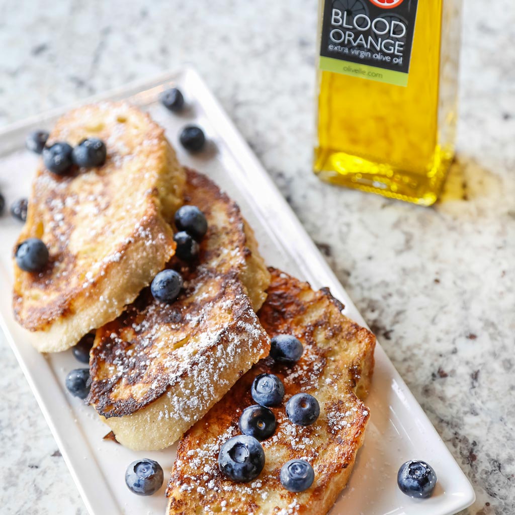 Blood Orange French Toast with Blueberries and Powdered Sugar using the Blood Orange Infused Olive Oil served on a white dish with marble background.