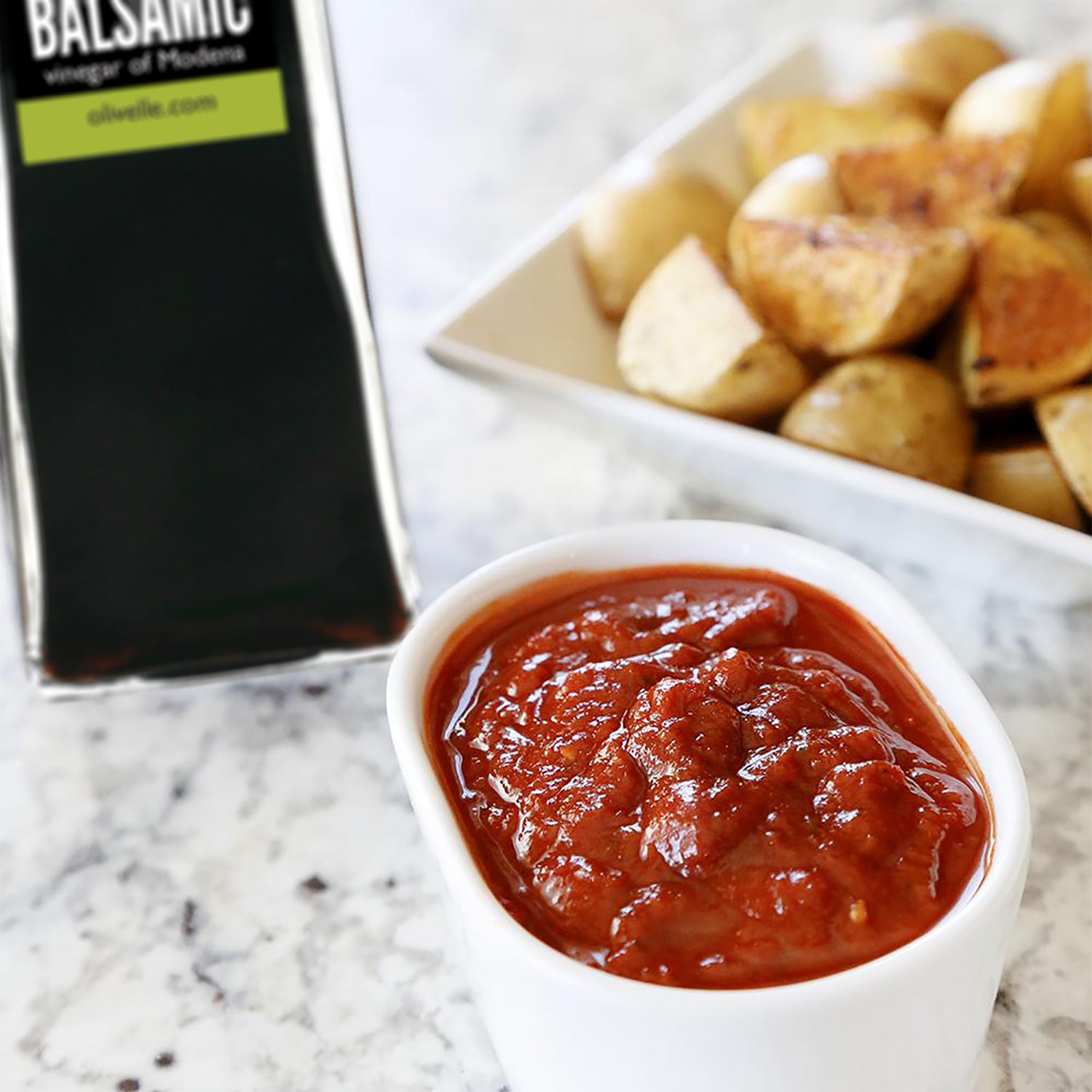 Bruschetta Ketchup made with Sun Dried Tomato Balsamic Vinegar, Roasted Garlic Sea Salt and our Bruschetta Dried Herb Blend served in a white bowl next to roasted potatoes.