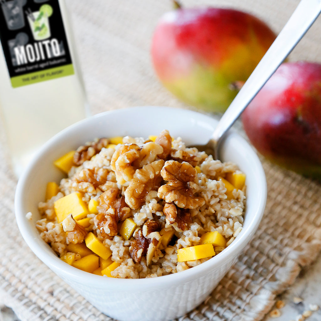 mango and walnut steel cut oats with toasted coconut balsamic vinegar served in a white bowl with a spoon