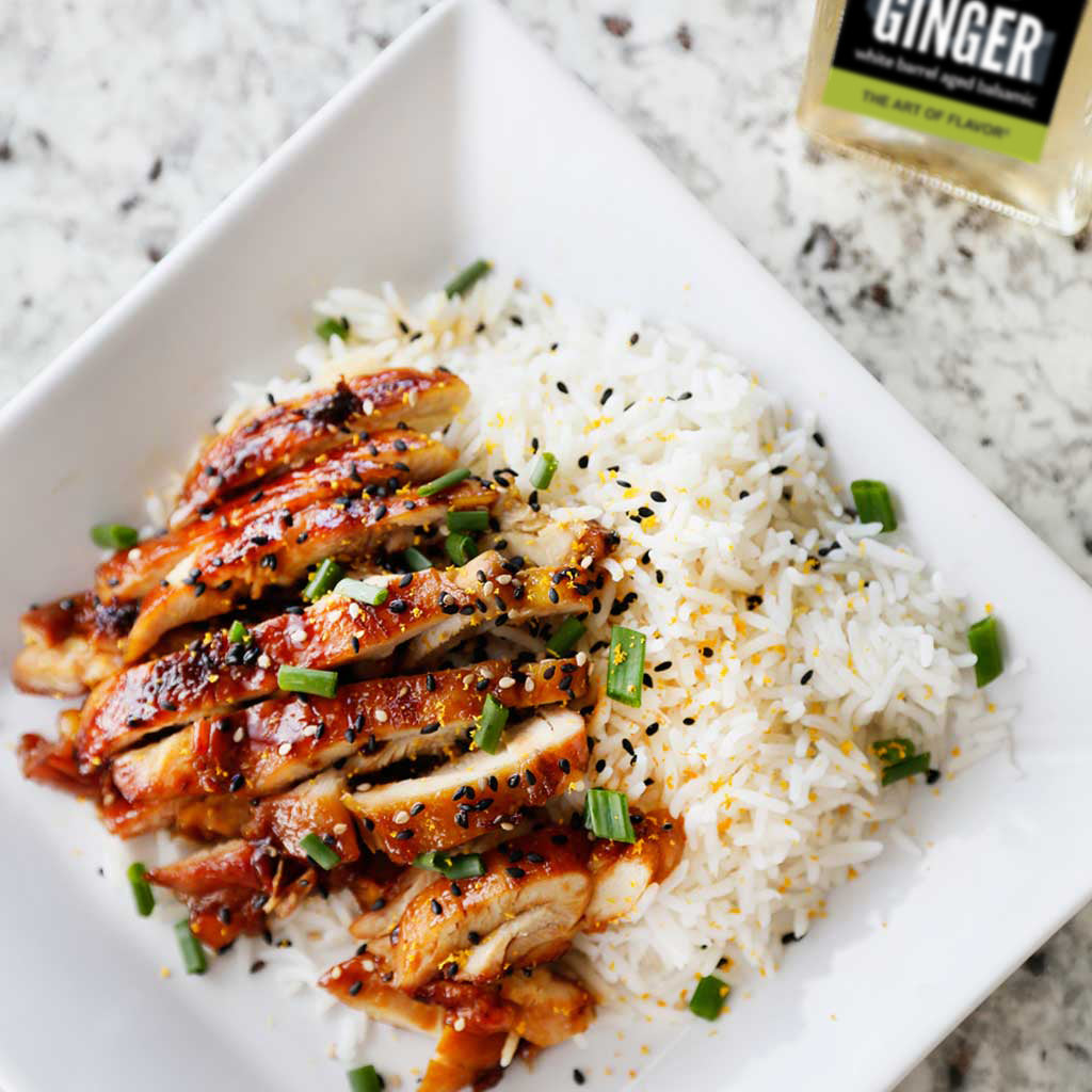 terriyaki chicken on top of white rice finished with green onions, sesame seeds, and tangy tangerine balsamic vinegar served next to the jar of tangerine vinegar