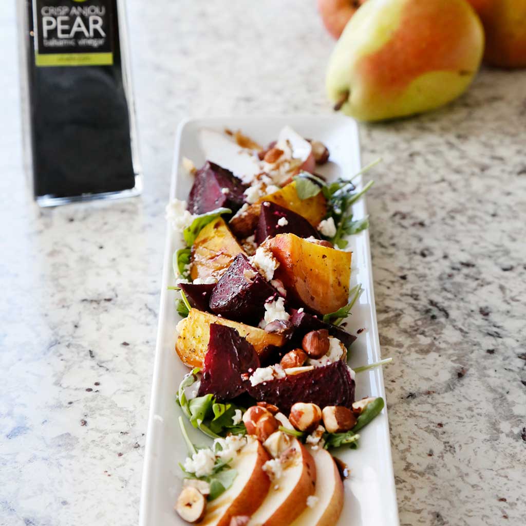 Roasted Beet, Pear & Nut Salad made with our Blood Orange Infused Olive Oil, Crisp Anjou Pear Balsamic Vinegar and Sel Gris Celtic Sea Salt served in a white platter on a marble table top.