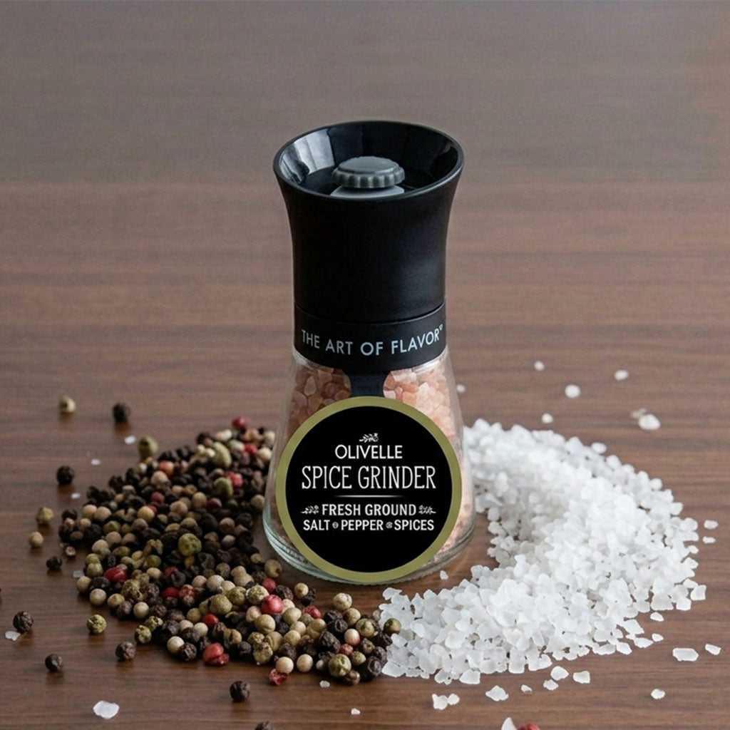 Black spice grinder surrounded by peppercorns and coarse white salt