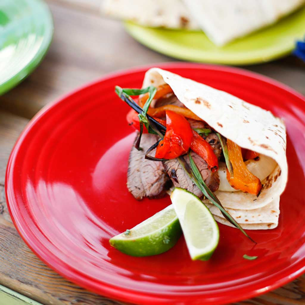 Coffee Rubbed Tri Tip Fajitas on colorful plates garnished with lime wedges