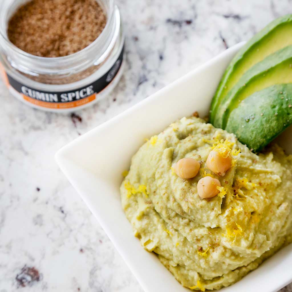 avocado hummus made from Greek Olive Oil, Cumin Spice World Seasoning and avocados served in a white dish on a marble table top