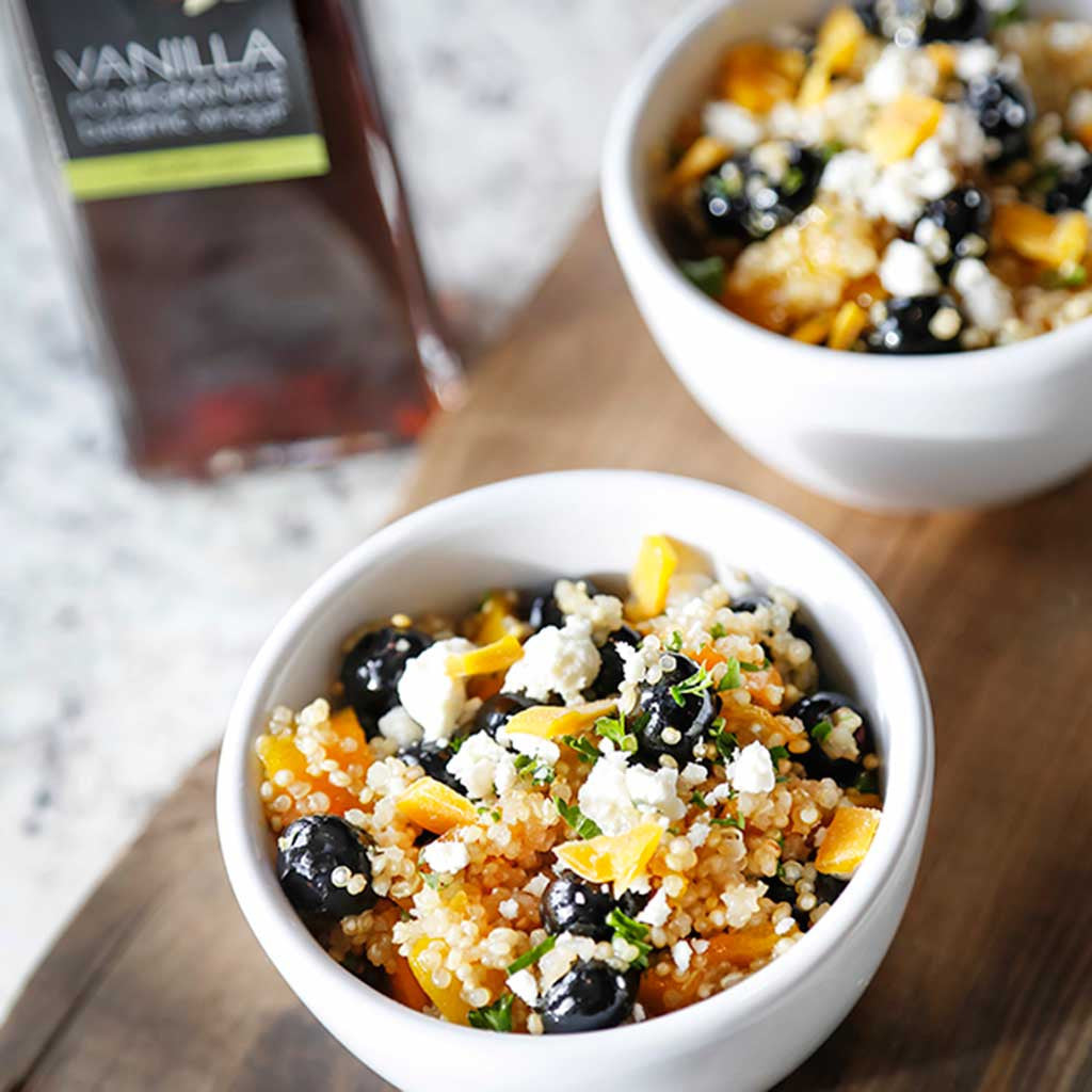 mango, blueberry, and feta quinoa salad in mini bowls alongside vanilla pomegranate balsamic vinegar