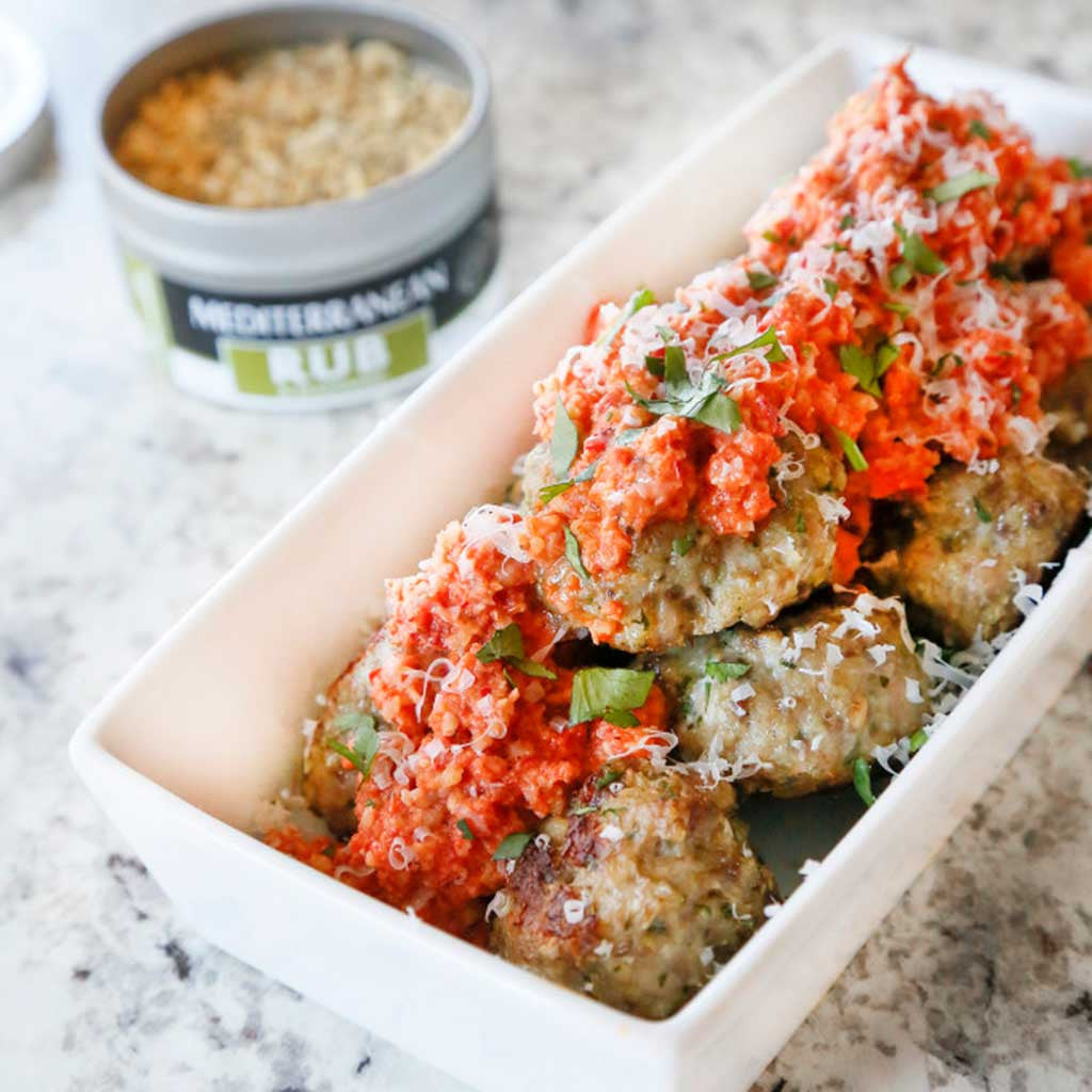 meatballs topped with red pepper pesto alongside a tin of Mediterranean rub seasoning