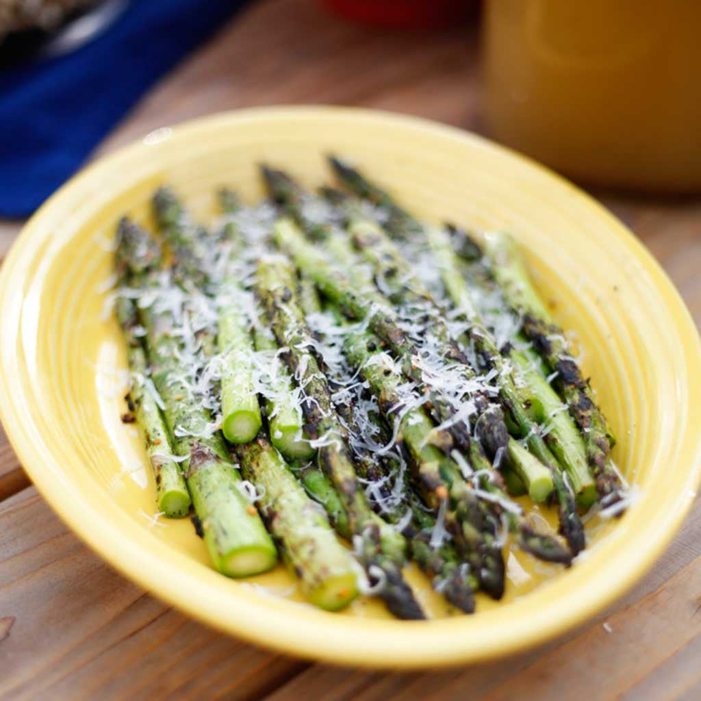 A beautiful dish of grilled asparagus topped with fresh Parmesan cheese.