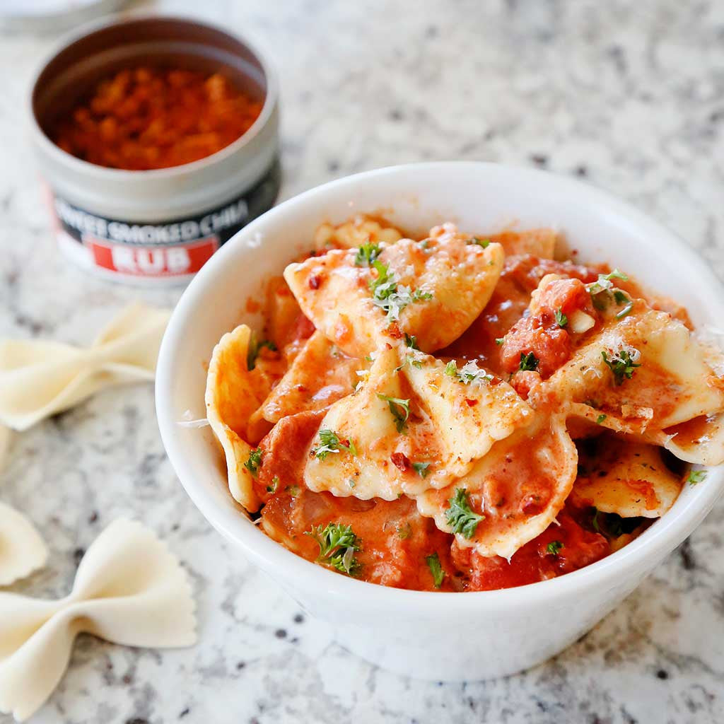 bowtie pasta with vodka cream sauce, parsley, alongside sweet smoked chili rub seasoning tin