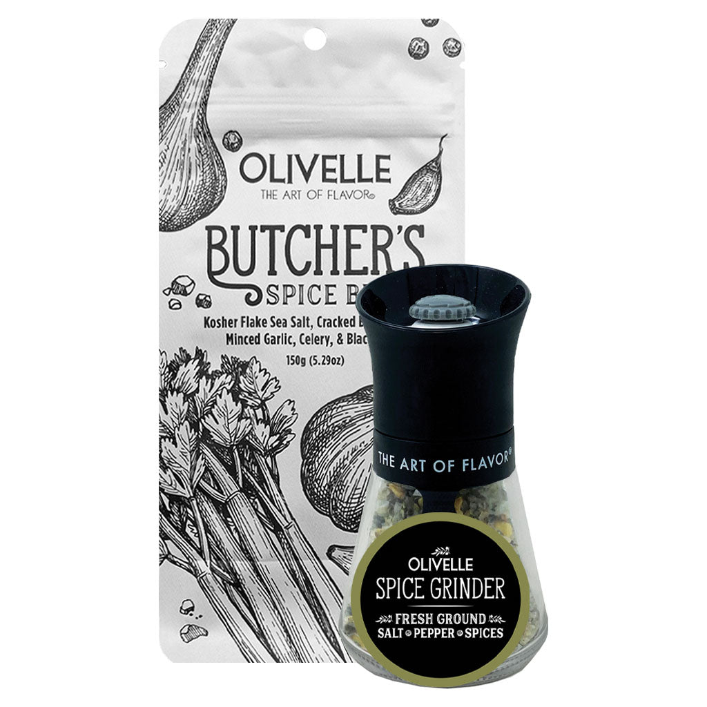 Olivelle Butcher's Spice Blend in a clear glass spice grinder with a black top and base, shown in front of its white illustrated pouch packaging.