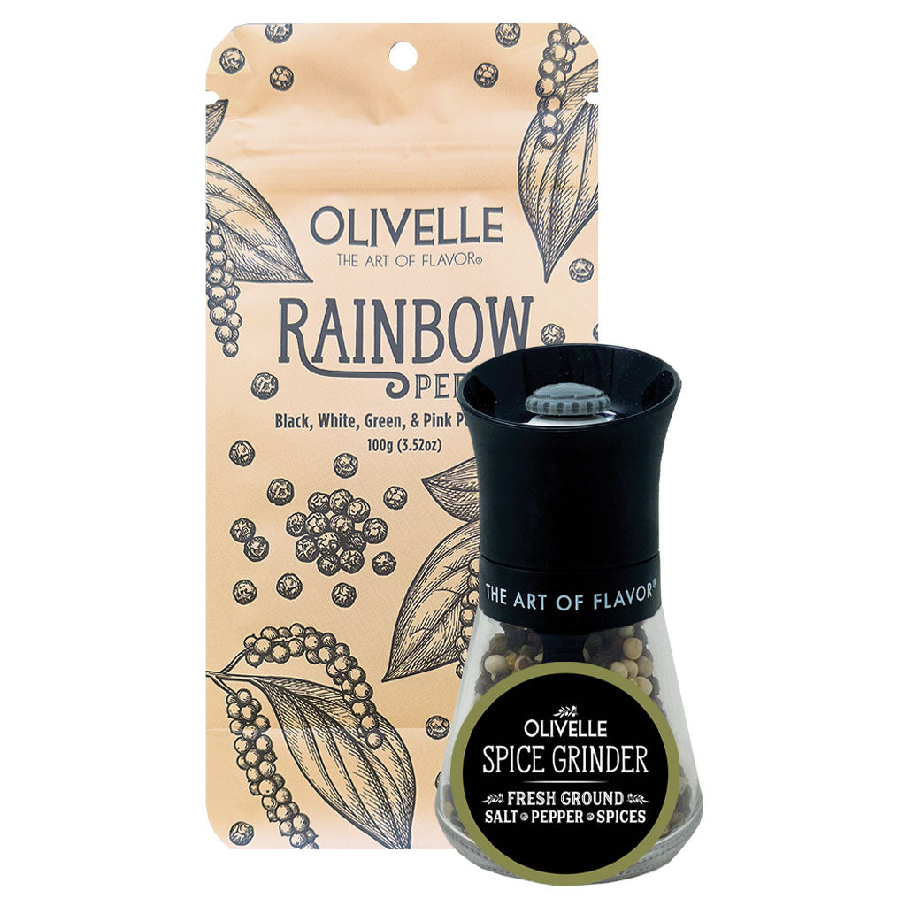 Olivelle Rainbow Pepper spice grinder with its packaging pouch. The grinder features a black top and a clear glass lower chamber containing ground black, white, green, and pink peppercorns.