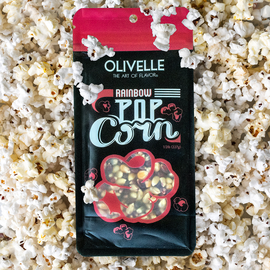 Bag of Rainbow Popcorn kernels with a window showing colorful kernels, surrounded by popped popcorn
