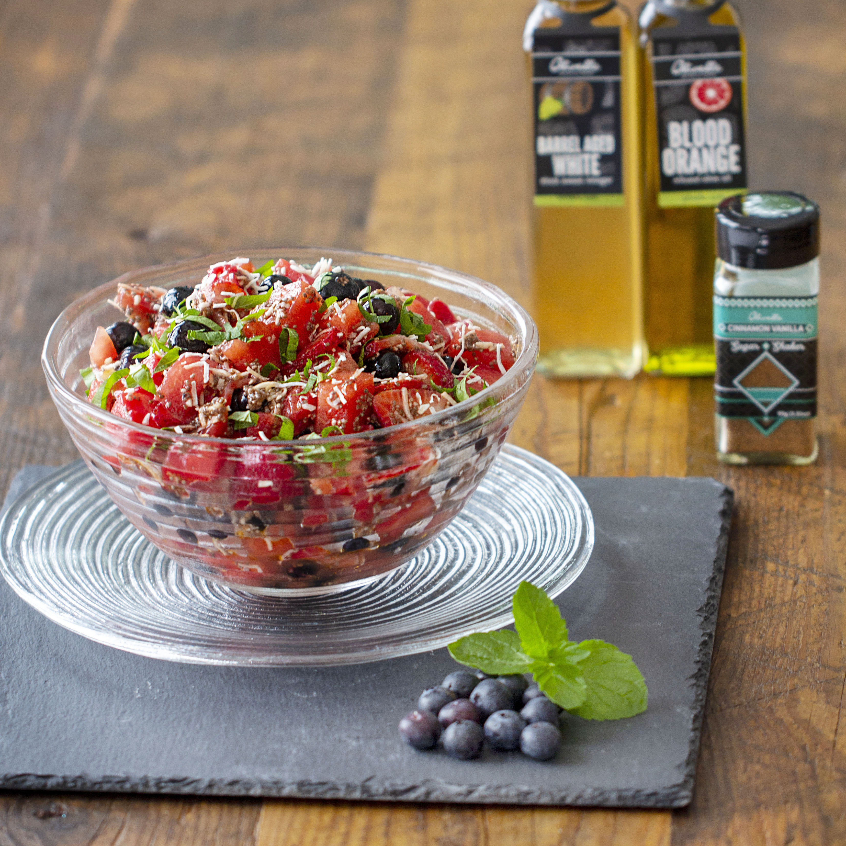 Watermelon and berry salad show next to the oil, vinegar, and seasoning used to make it